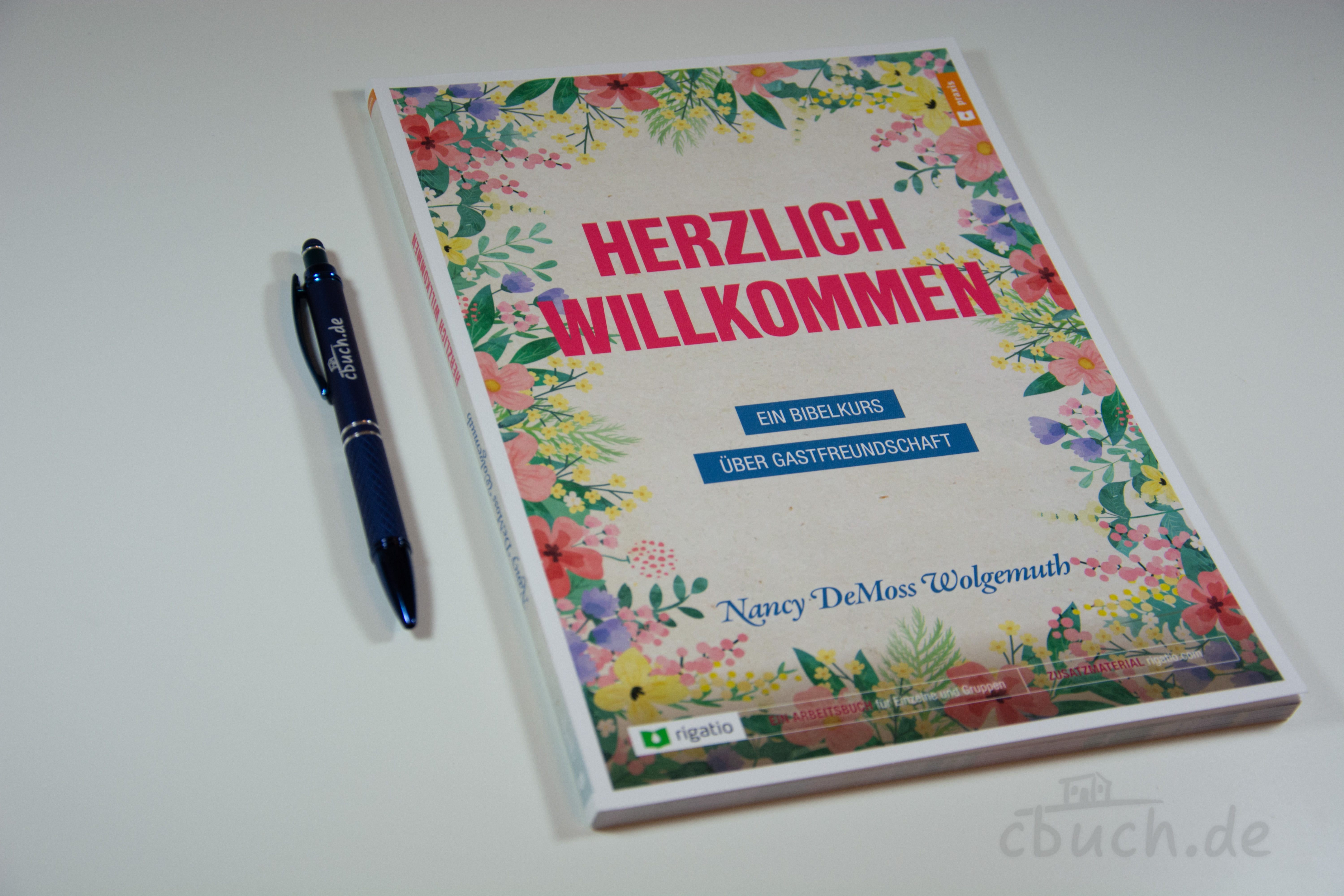 Buch Herzlich Willkommen mit Blumen und Stift daneben