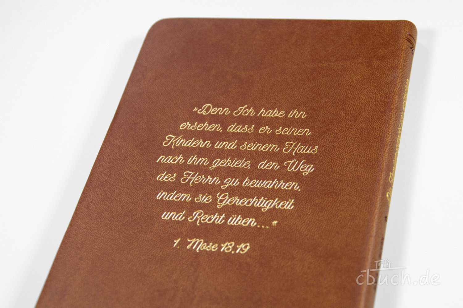 Bibel mit Prägung 1. Mose 18,19 auf braunem Einband Braunes Buch mit goldener Prägung des Bibelverses 1. Mose 18