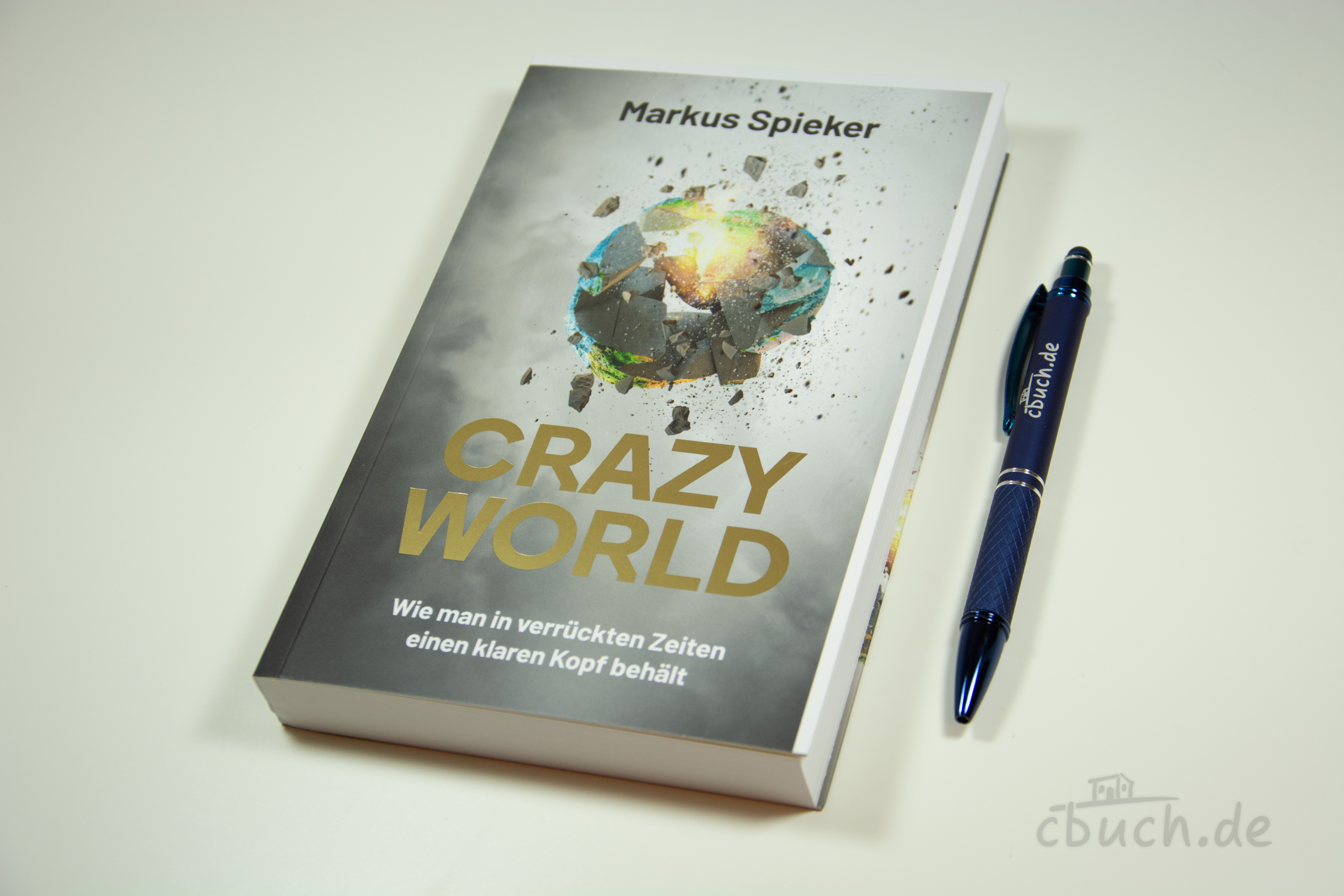 Buch Crazy World von Markus Spieker und blauer Kugelschreibe