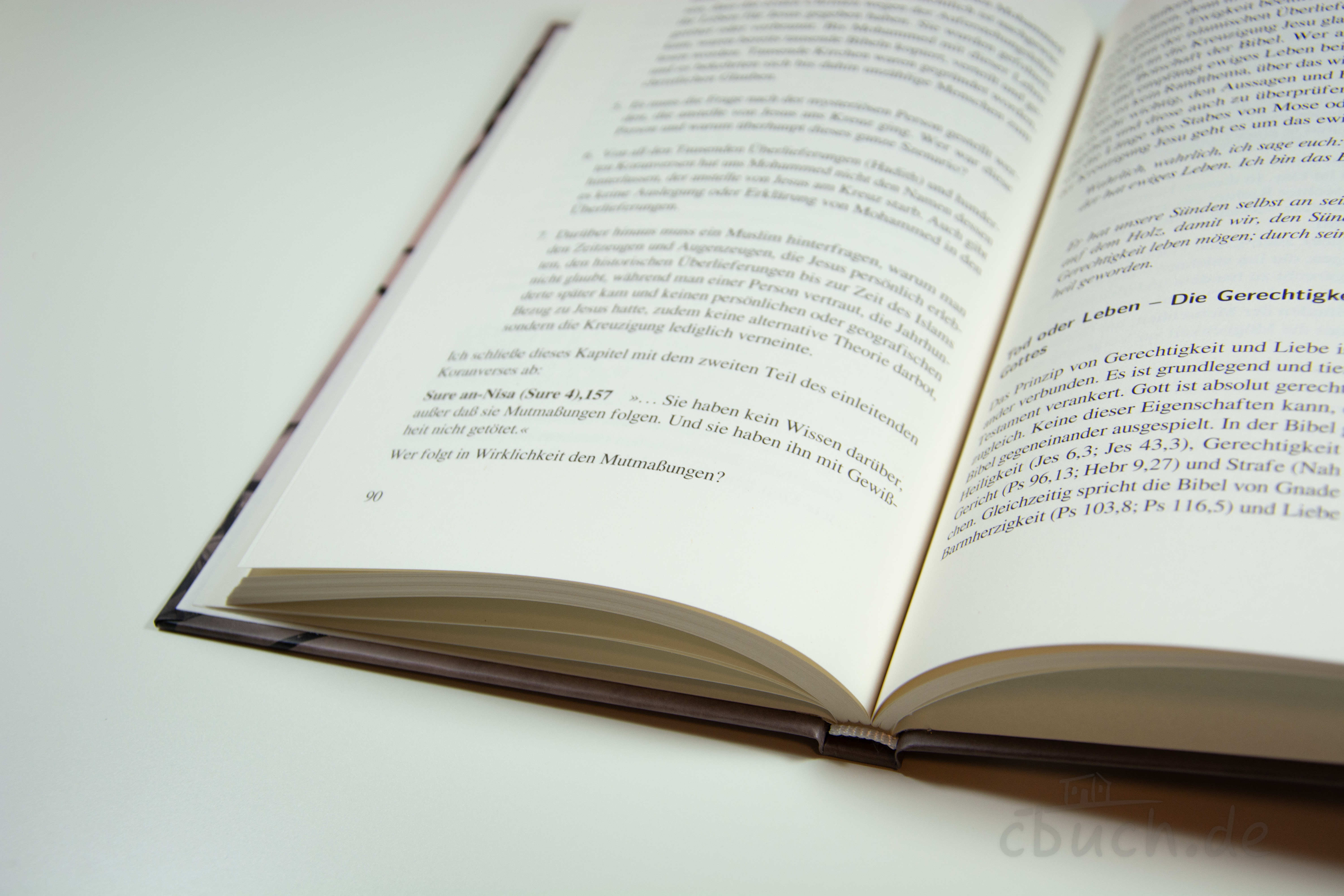 Ein aufgeschlagenes Buch auf weißem Hintergrund, das Textauszüge auf den Seiten zeigt