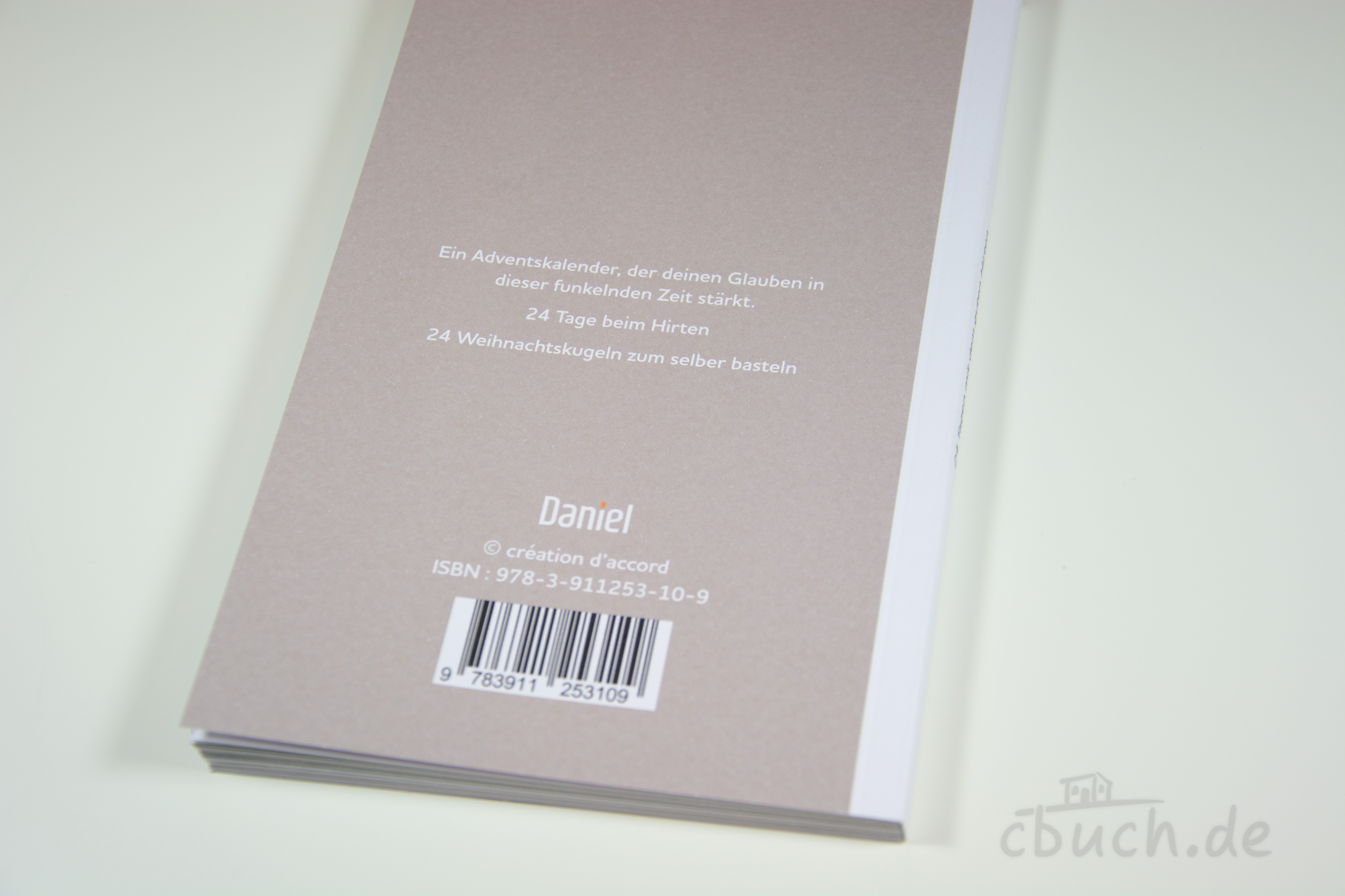 Rückseite des Adventskalender-Buchs „24 Tage mit dem guten Hirten“ von Daniel-Verlag mit Hinweis auf 24 Tage beim Hirten und 24 Weihnachtskugeln zum Selberbasteln.